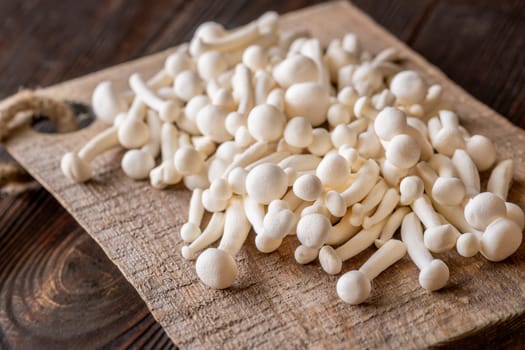 A delicate cluster of bunapi-shimeji mushrooms resting on a wooden surface
