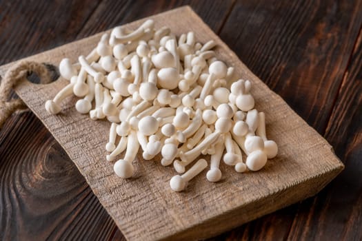 A delicate cluster of bunapi-shimeji mushrooms resting on a wooden surface