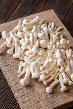 A delicate cluster of bunapi-shimeji mushrooms resting on a wooden surface