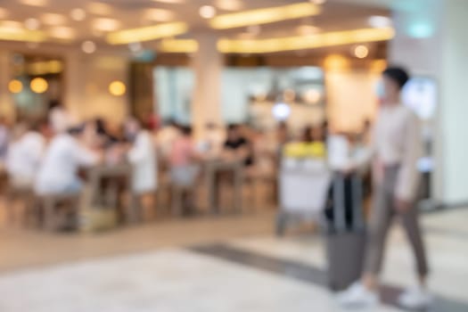 Blur passenger walking with luggage in front of cafe or restaurant in airport terminal for background
