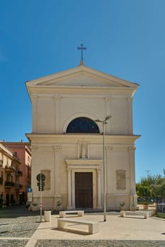 Civitavecchia, Italy - January 27, 2025: Historic church in Civitavecchia, Italy, with a sunlit facade. The street view includes parked cars and a clear blue sky, showing Italian culture.