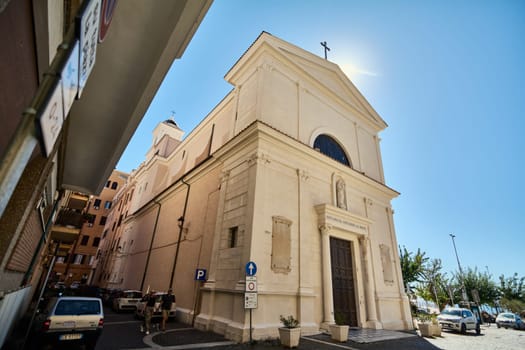 Civitavecchia, Italy - January 27, 2025: Church in Civitavecchia with a sunlit facade. The image captures parked cars and a clear blue sky, emphasizing the charm of Italian architecture.
