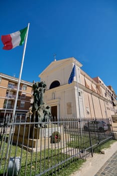 Civitavecchia, Italy - January 27, 2025: Church in Civitavecchia, Italy. The image shows the sculpture in memory of the war dead and a clear blue sky that highlights the Italian architectural beauty.