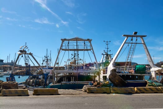 Dockside view of fishing boats in Civitavecchia, Italy, with equipment and nets visible. This image highlights the complexity and daily life in the fishing industry
