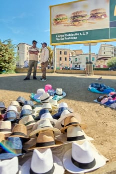 Civitavecchia, Italy - February 2, 2025: Street vendors selling a variety of colorful hats at an outdoor market. The image captures the vibrant display of hats and the casual atmosphere of the vendors