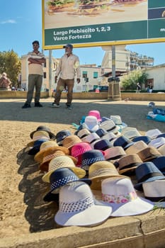 Civitavecchia, Italy, February 2, 2025: Scene of street vendors offering a colorful variety of hats at a busy market. The image highlights the diverse and attractive environment of the market.