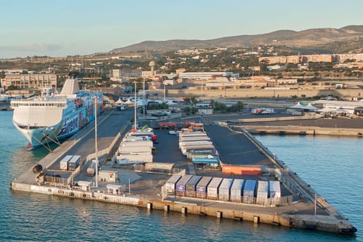 Civitavecchia, Italy - February 02, 2025: Trucks, containers, and a ferry in a busy Italian port emphasizing logistics, trade, and transportation networks. Concept: industry, commerce, logistics port