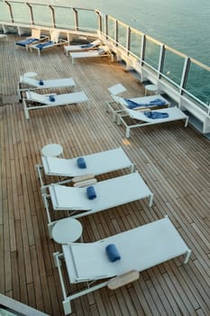 Luxury. Minimalist sunbeds arranged on a wooden deck with blue towels, evoking relaxation, elegance, and exclusive resort experiences.