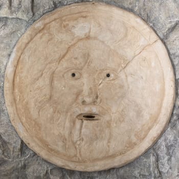 Mouth of truth sightseeing in Rome, Italy. Historical sculpture made of marble with antique face full of mystery and legend.