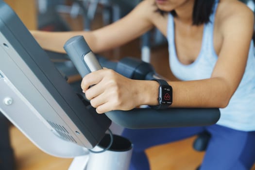 Pulse app display on smartwatch in the hands of a woman exercising in a sports club