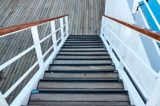 Scenic view of a wooden staircase on a ship deck, featuring white railings and detailed craftsmanship. Ideal for showcasing nautical themes and ship design.