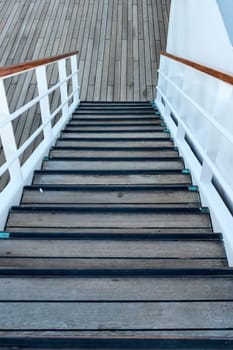 An elegant wooden staircase with white railings on a ship deck, ideal for nautical, travel, and marine architecture themes. Perfect for illustrating maritime elegance and design.