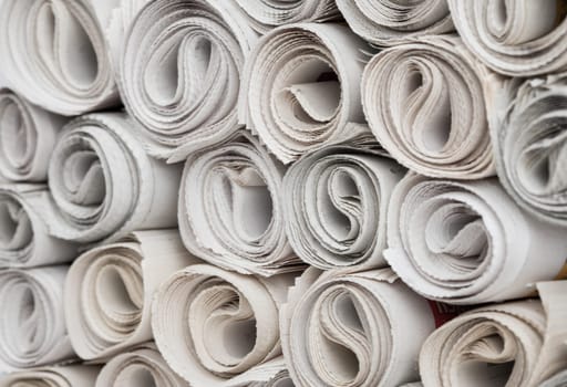 Stack of newspapers rolls, paper texture background.