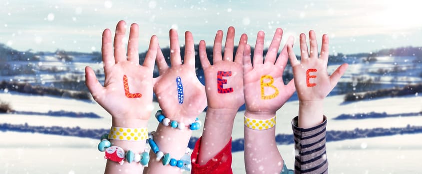 Children Hands Building Colorful German Word Liebe Means Love. Snowy Winter Background With Snowflakes