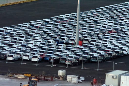 Civitavecchia. Italy - February 7, 2025: Aerial view of new vehicles parked in a port, ready for transport. Essential for delivery to the market. Concept: International trade, logistics operations