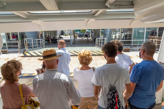 Venice, Italy - July 5 2021: the ferry anchors at the ferry stop Lido with tourists and local people on board of the vaporetto.