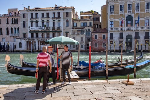 Venice, Italy - July 7, 2021: Gondoliere waiting at the gondola stop for passengers in Venice, Italy.