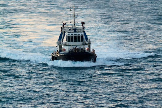 Civitavecchia. Italy - February 07, 2025: A robust tugboat is seen from the front, moving fast in deep waters. These vessels are crucial for ocean navigation. Concept: ocean transport