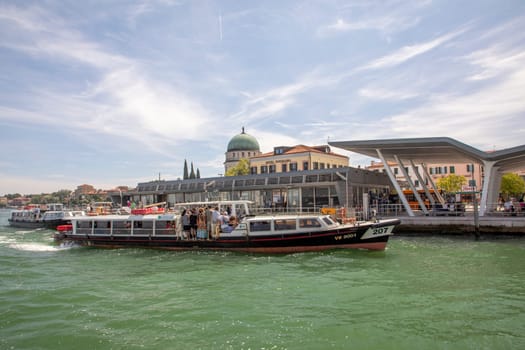 Venice, Italy - July 5, 2021:  the ferry on the way to Venice with view to St. Mark's square. 2021: the ferry anchors at the ferry stop Lido with tourists and local people on board of the vaporetto.
