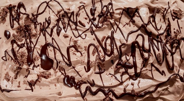 Chocolate sauce drizzled over delicious creamy ice-cream or frozen yogurt in a close up full frame background texture for menu or design concepts