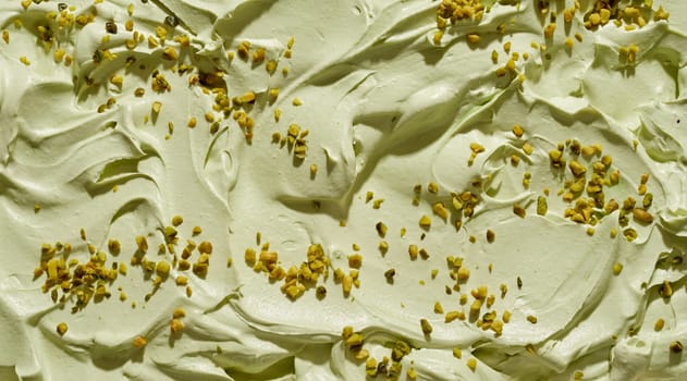 Creamy pistachio ice-cream with chopped fresh nuts in a full frame background texture with close up on the surface with swirls and ridges