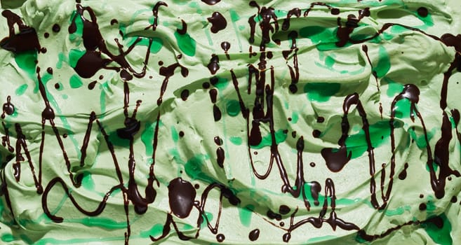 Tasty refreshing green mint ice cream with chocolate drizzle for a tasty summer treat in a close up full frame background texture for menu advertising
