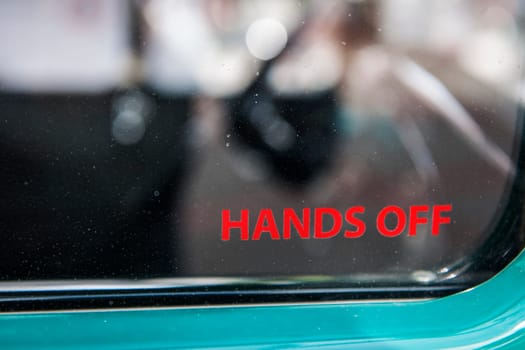 Lateral partial view of the side window of a vintage car with the inscription "hands off""."