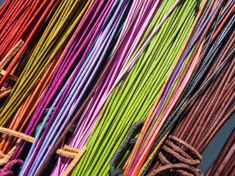 Red and orange colored leather cords with knots on a table in the sunlight in an oblique view.