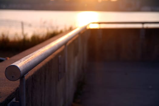 Close up and perspective of a handrail as protection over the river during a sunset