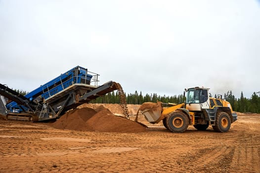 The front loader in the quarry collects a bucket of sand. High quality photo