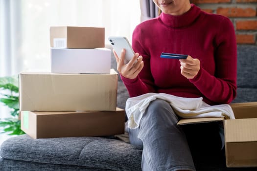 A woman holding phone and using credit card place an order shopping online