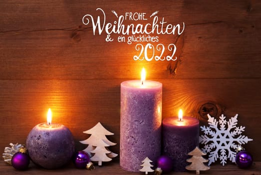 German Calligraphy Frohe Weihnachten Und Ein Glueckliches 2022 Mean Merry Christmas And Happy 2022. Purple Romantic Candle Light With Christmas Decoration. Brown Wooden Background