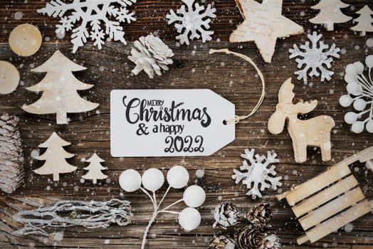 One White Label With English Text Merry Christmas And A Happy 2022. Frame Of Christmas Decoration Like Tree, Sled, Star And Fir Cone. Wooden Background With Snowflakes