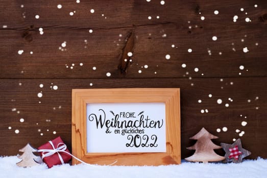 Frame With German Calligraphy Frohe Weihnachten Und Ein Glueckliches 2022 Means Merry Christmas And A Happy 2022. Christmas Decoration Like Gift, Tree And Star. Wooden Background With Snow