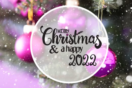 English Calligraphy Merry Christmas And Happy 2022. Blurry Christmas Tree With Pink Christmas Ball Ornament And Snowflakes