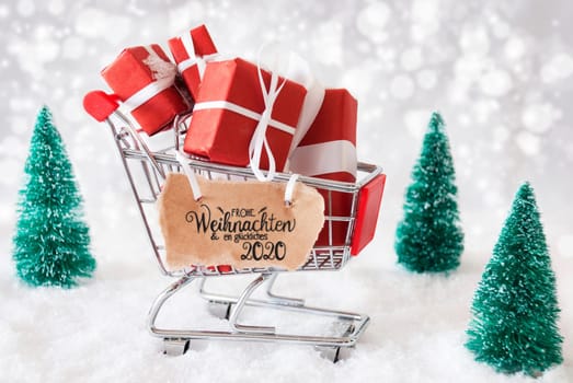 Shopping Cart With Gifts And Label WIth German Calligraphy Frohe Weihnachten Und Ein Glueckliches 2020 Means Merry Christmas And A Happy 2020. Green Christmas Tree And Snow