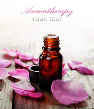 Essential oil with rose petals on wooden background