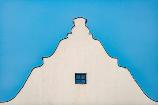 Old building roof and wall with blue sky in background