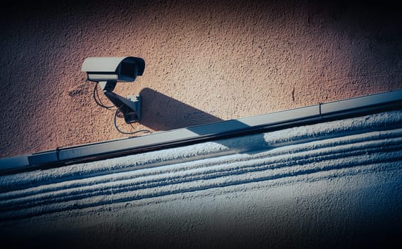 Security camera in city on building wall, grungy look