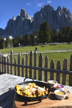 The Kaiserschmarrn is a pastry. It is one of the desserts in Austrian cuisine. It is served here with icing sugar,apple sauce and raisins in front of the Geisler peaks in the Dolomites of Italy.