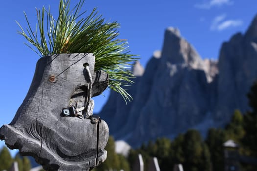A carved hiking boot in front of the Odle peaks in the Alps,Dolomites,South Tyrol,Italy,Europe. In the mountains you can take many hikes. They are used for recreation in nature.
