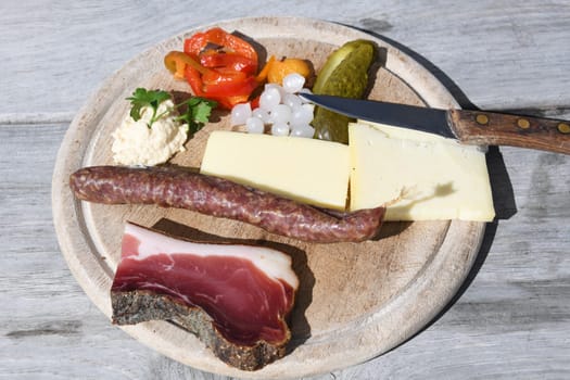 When hiking in the European Alps,people like to eat a snack plate to strengthen themselves in the huts. Salami,cheese,South Tyrolean ham and vegetables are served on the wooden plate.