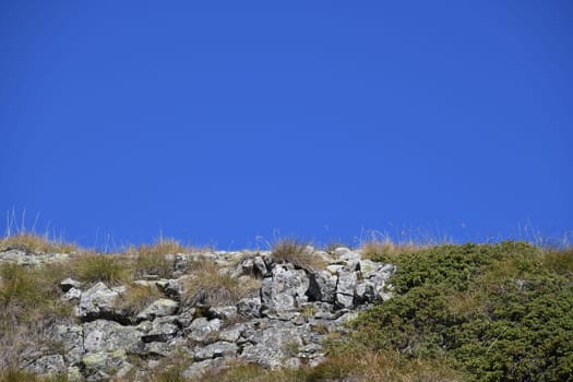 Blue sky as a background with stones,grass,rocks in the mountains and in the European Alps