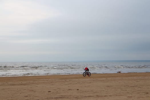 cyclist rides a fat bike on a deserted sandy beach in autumn