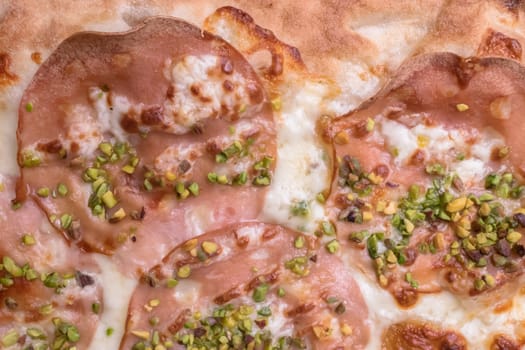 Delicious gourmet pizza with ham and pistachios. View from above.