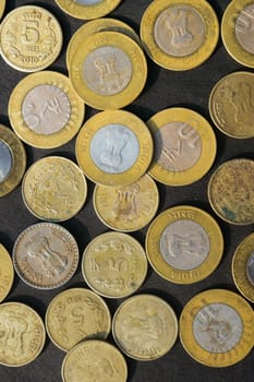 Mix of Gold Colored Indian Rupee Coin currency on rustic floor. Full Frame. Table Top View. Vertical. Business Finance and financial Investment Background. Close Up