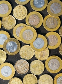 Mix of Gold Colored Indian Rupee Coin currency on rustic floor. Full Frame. Table Top View. Vertical. Business Finance and financial Investment Background. Close Up