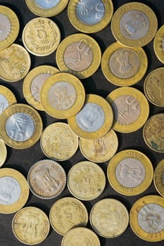 Mix of Gold Colored Indian Rupee Coin currency on rustic floor. Full Frame. Table Top View. Vertical. Business Finance and financial Investment Background. Close Up