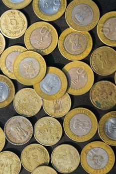 Mix of Gold Colored Indian Rupee Coin currency on rustic floor. Full Frame. Table Top View. Vertical. Business Finance and financial Investment Background. Close Up