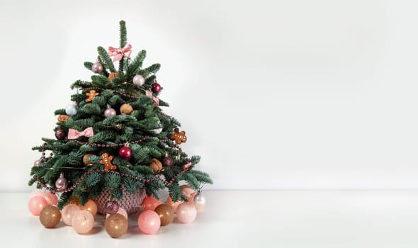 Beautiful small decorated Christmas tree on a white wooden table. Good mood. Danish pine and fir, Nobilis